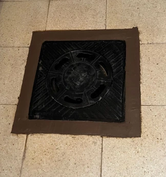 Tapadera de alcantarilla instalada con acabado sellado en suelo de cerámica-pozarq360